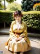 A woman in a yellow kimono sitting on the ground.